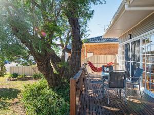 a deck with a table and chairs and a tree at The Croft Cosy Beach House with Aircon and only 270m to the Beach in Fingal Bay