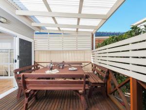 patio z drewnianym stołem i ławkami na pokładzie w obiekcie The Croft Cosy Beach House with Aircon and only 270m to the Beach w mieście Fingal Bay