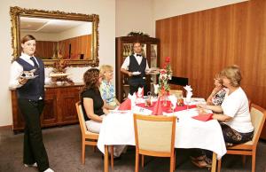 un grupo de personas sentadas alrededor de una mesa en una habitación en Hotel Maxim, en Svätý Jur