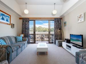 a living room with a couch and a tv at The Poplars, 6,36 Magnus Street - Unit with fabulous views and a complex pool in Nelson Bay