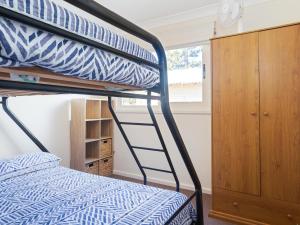 ein Schlafzimmer mit einem Etagenbett mit einer Leiter in der Unterkunft The Whale Watcher waterfront unit with stunning views level access in Anna Bay