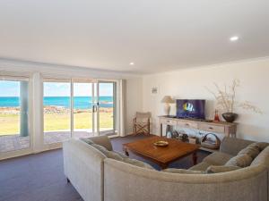 una sala de estar con sofá y TV y el océano en The Whale Watcher waterfront unit with stunning views level access, en Anna Bay