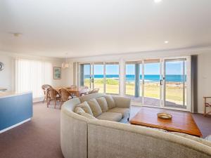 un soggiorno con divano e tavolo di The Whale Watcher waterfront unit with stunning views level access ad Anna Bay