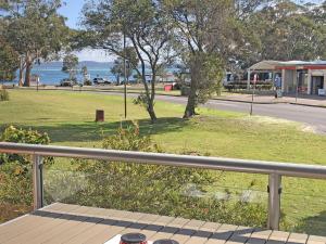 un balcón con vistas a un parque con un árbol en Villa Ellisa 2 Beautiful water views and directly across to Little Beach, en Nelson Bay
