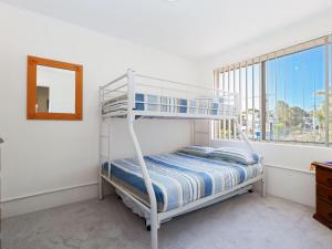 een slaapkamer met een stapelbed, een spiegel en een raam bij Yarramundi, 4,47 Magnus Street - air conditioned unit with air con, wi-fi, water views and close to town in Nelson Bay