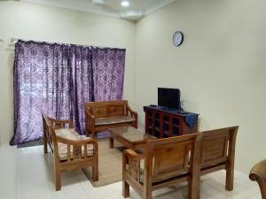 een woonkamer met houten stoelen en een televisie bij Kayu Merbau Homestay in Seri Iskandar