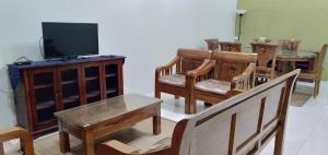 a living room with wooden furniture and a flat screen tv at Kayu Merbau Homestay in Seri Iskandar +9 photos