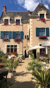 un edificio con persianas azules y flores en las ventanas en Le Regisseur, en Brissac-Quincé