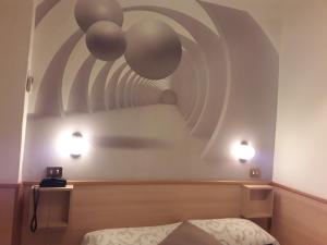 トリノにあるホテル ヴィットリアーノのベッド1台と壁に2つの照明が備わる客室です。