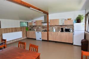 a large kitchen with a table and a white refrigerator at Casa Miraj in Călimăneşti