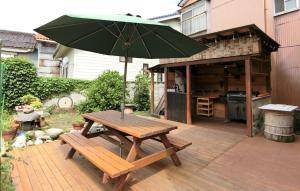 a wooden picnic table with an umbrella on a patio at Shirokuma Inn in Toyama