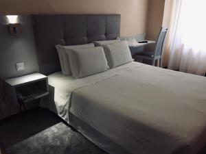 a bedroom with a large white bed and a chair at Hotel Excelsior in Lisbon