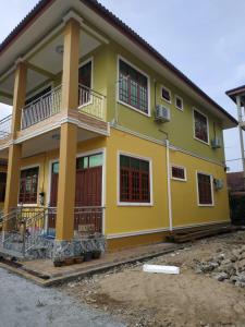 Casa amarilla con puertas y ventanas rojas en Cikgu CTZ Homestay A, en Kampung Raja