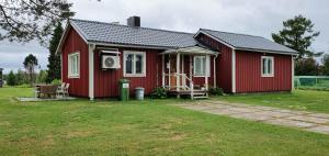 une maison rouge avec une cour d'herbe devant elle dans l'établissement Ida's Stuga, à Karungi