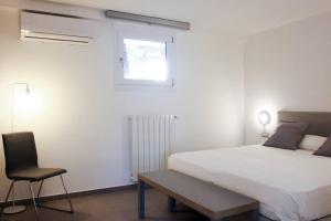 a white bedroom with a bed and a chair at Via Mare in Ginosa Marina