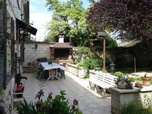 un patio con una mesa blanca, una mesa y un banco en Au Grand Sapin Chambres chez l'habitant, en Hénonville