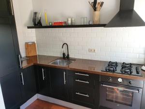 een keuken met zwarte kasten en een wastafel bij Single family home in Hillegersberg - Schiebroek in Rotterdam