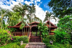 a resort with stairs leading to a building with palm trees at Ruan Kanchanok in Pak Chong