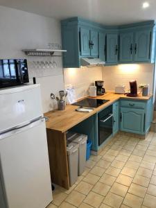 uma cozinha com armários azuis e um frigorífico branco em L'HISTORIQUE - Maison rénovée dans le centre-ville de Bayeux em Bayeux