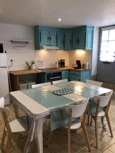 Una cocina con gabinetes azules y una mesa y sillas. en L'HISTORIQUE - Maison rénovée dans le centre-ville de Bayeux, en Bayeux