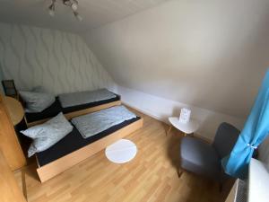 a small room with two beds and a chair at Fewo Lindenhof in Hatzfeld
