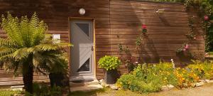 a wooden house with a door and some flowers at L'Oustaou du Bodo in Ambon