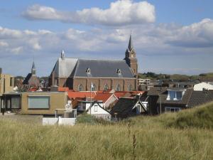 a large building with a clock tower in a city at Torenlicht - Zand I (36) in Egmond aan Zee