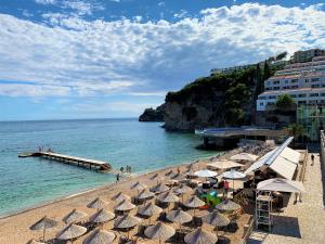 einen Strand mit Sonnenschirmen und das Meer mit einem Pier in der Unterkunft Karina Apartment in Budva