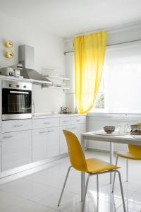 a white kitchen with a table and yellow chairs at Mer Epanomi in Órmos