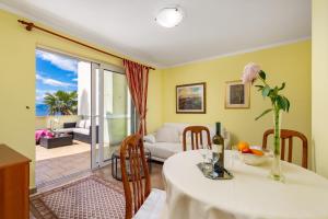 a dining room with a table with a vase of flowers at Apartments Villa Nora in Rijeka
