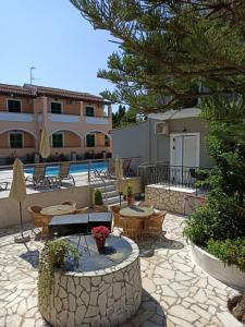 a patio with tables and chairs next to a building at Dionisos Apts Gouvia by Estia in Corfu