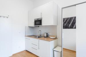 eine weiße Küche mit einer Spüle und einer Mikrowelle in der Unterkunft Residence Tesnov Apartment in Prag