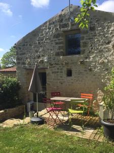 een tafel en stoelen voor een stenen gebouw bij La Remise in Coulonges-sur-lʼAutize