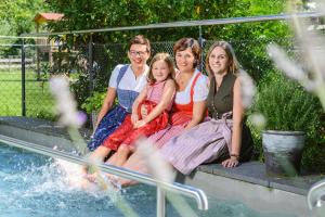 a group of people sitting next to a pool at Hotel Wirtshaus Sattlerwirt in Ebbs