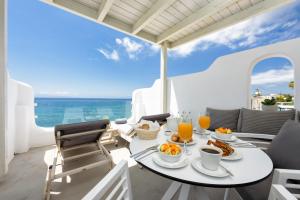 un tavolo con prodotti per la colazione su un balcone con vista sull'oceano di Blue Waves Suites & Apartments - To Kyma a Drios