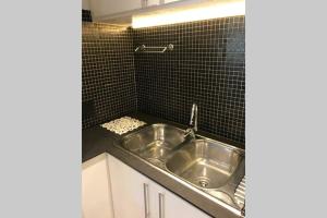a stainless steel sink in a black tiled kitchen at Winner in the Winelands in Franschhoek