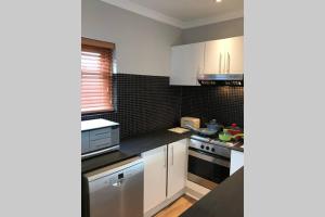 a kitchen with white cabinets and a black counter top at Winner in the Winelands in Franschhoek