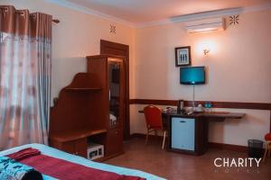 um quarto com uma cama e uma secretária com um computador em New Charity Hotel International em Arusha