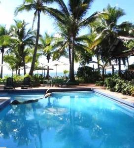 una gran piscina con palmeras y el océano en Club Fiji Resort, en Nadi