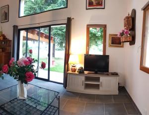 a living room with a tv and a vase with flowers at Jardin de Pomarède in Prigonrieux