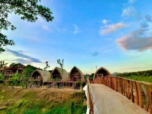 a bridge over a road with a group of huts at Rice straw Green lodge- resort in Quan Tom