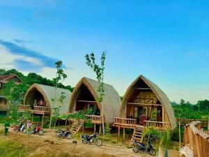 a group of huts with motorcycles parked in front of them at Rice straw Green lodge- resort in Quan Tom