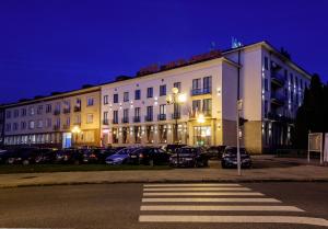 a large white building with cars parked in a parking lot at Hotel Polana in Zvolen