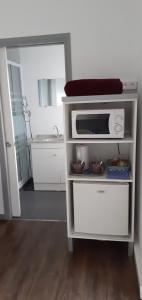 eine Küche mit einer Mikrowelle auf einem weißen Regal in der Unterkunft "Tom" Chez Tom et Dilou in Kumak