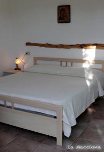een slaapkamer met een wit bed en een lamp bij La Macciona in Aglientu