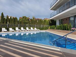 a swimming pool with lounge chairs next to a house at Apartamenty Azure - 365PAM in Kołobrzeg