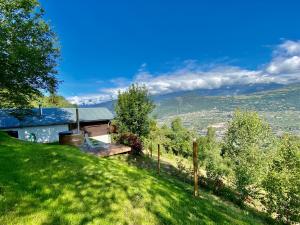 a house on a grassy hill with a view at Eco Lodge with Jacuzzi and View in the Swiss Alps in Grône