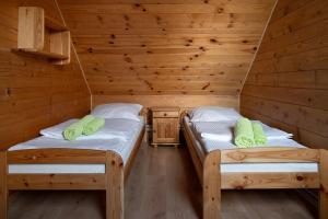 two beds in a cabin with wooden walls at Chatka Włóczykija in Jamna