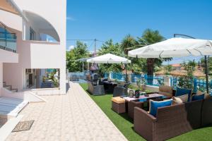 a patio with chairs and tables and an umbrella at Stratos Deluxe Apartments in Skala Potamias