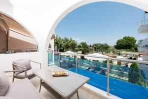 einen Balkon mit einem Tisch und Poolblick in der Unterkunft Stratos Deluxe Apartments in Skala Potamias